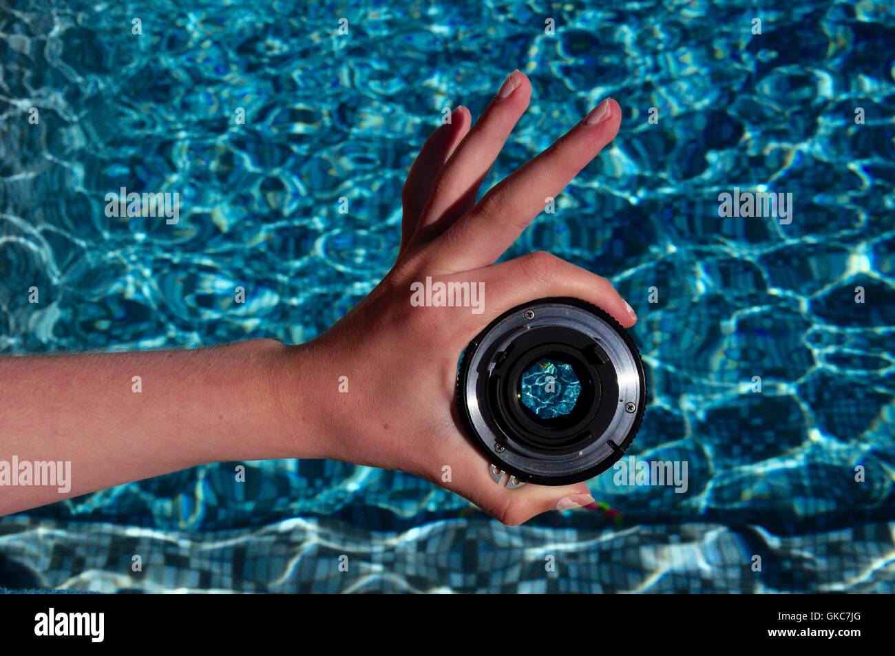 Lente prime y mano forman el signo de OK. Centrándose en el agua Foto de stock