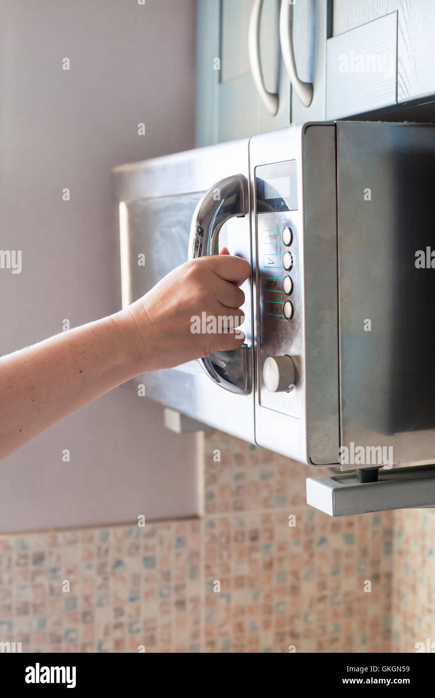 Mano cierra la puerta del horno de microondas para calentar la comida  Fotografía de stock - Alamy