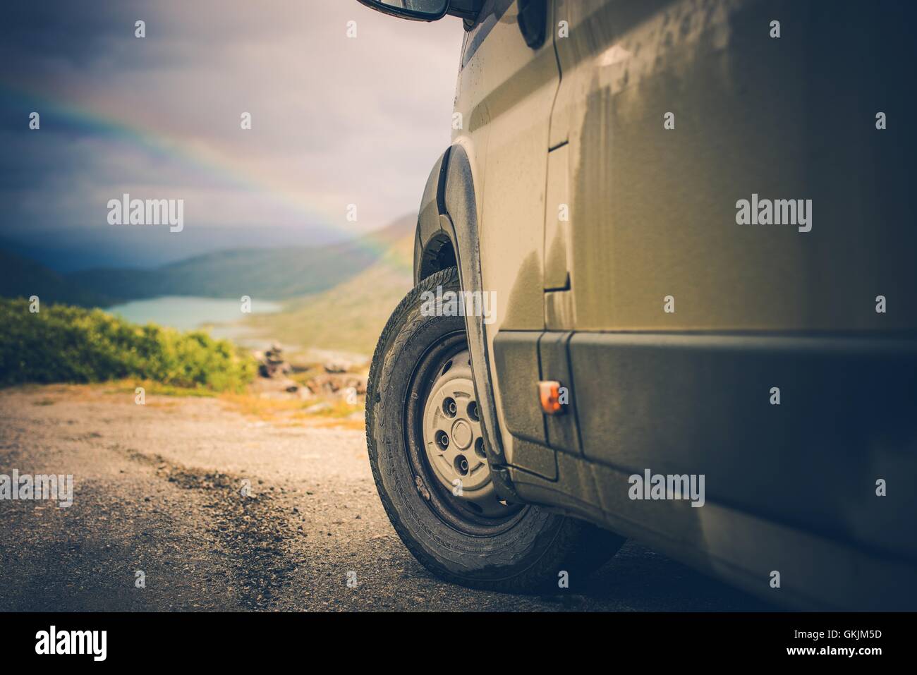 Camper y el pintoresco paisaje silvestre con arco iris. Camper conducción offroad. Foto de stock