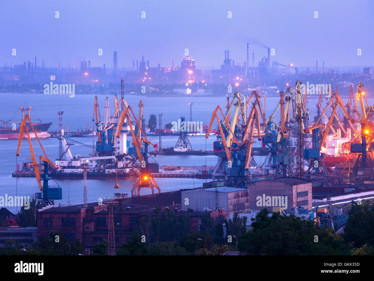 En la noche del puerto marítimo comercial de trabajo contra la planta de acero en Mariupol, Ucrania. Paisaje industrial. Buque de carga de carga Foto de stock