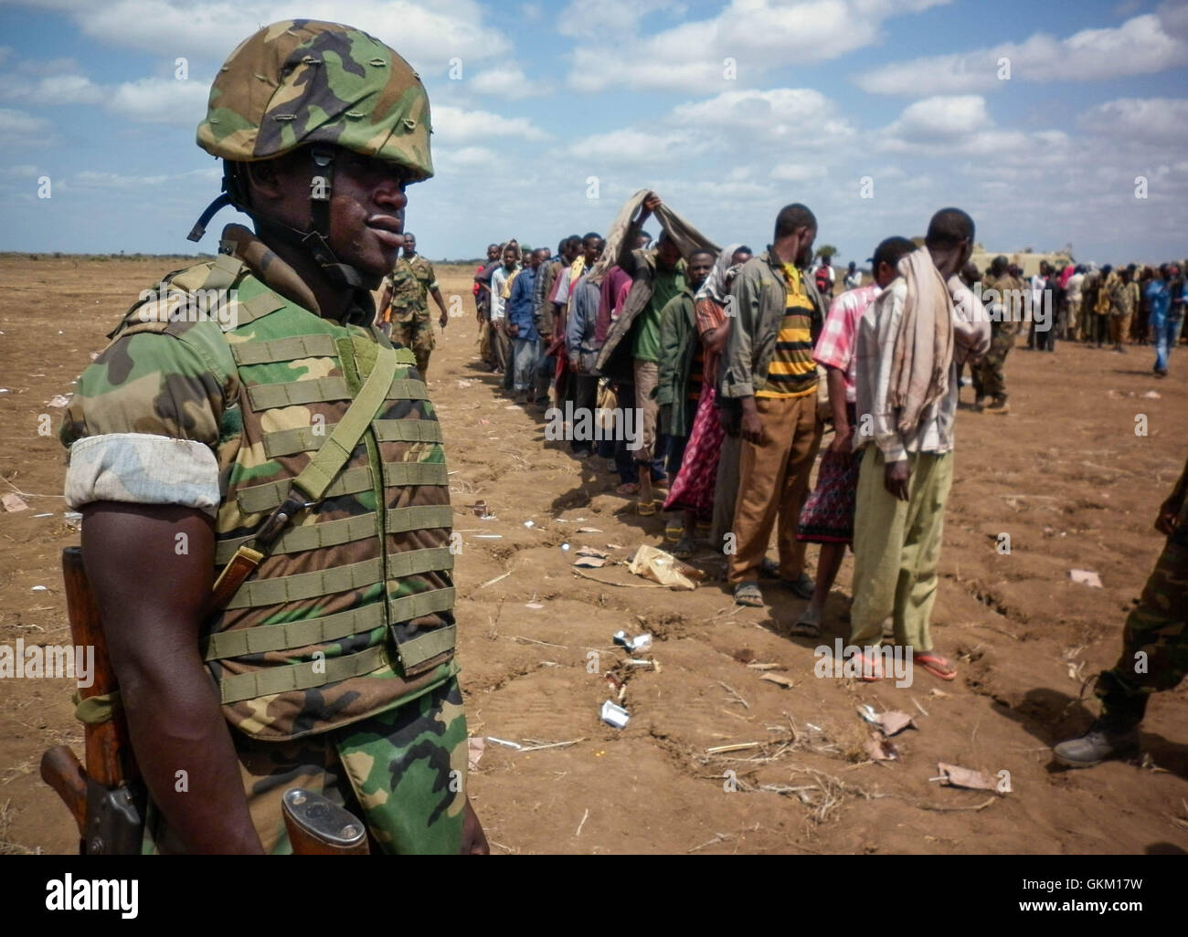 SOMALIA, Garsale: fotografía en un documento de fecha 22 de septiembre y liberado por el Grupo Africano Europea-estados unidas, Equipo de Apoyo a la información 23 de septiembre, un soldado ugandés de la Misión de la Unión Africana en Somalia (AMISOM) mira como miembros de Al Qaeda afiliadas del grupo militante Al Shabaab están en línea después de más de 200 combatientes se rindieron a las fuerzas de la AMISOM en Garsale, aproximadamente a 10km de la ciudad de Jowhar, 80km al norte de la capital, Mogadiscio. Los militantes desconectado tras los combates entre militantes en la región en la cual 8 Al Shabaab resultaron muertos, entre ellos dos altos Foto de stock