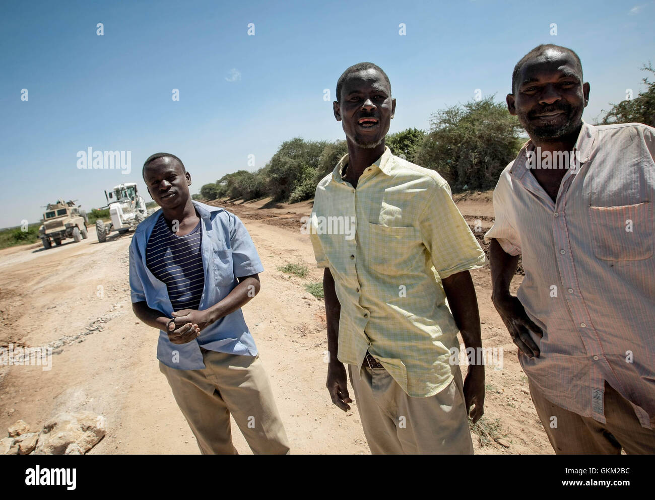 SOMALIA, MOGADISHU: En un photgraph adoptadas el 24 de enero y liberado por el Grupo Africano Europea-estados unidas, Equipo de Apoyo a la información el 26 de enero, hombres somalíes mirar como Misión de la Unión Africana en Somalia (AMISOM) ingenieros de combate el grado y la reparación de un tramo de la carretera que conduce a la ciudad de Afgooye en Somalia la región de Shabelle inferior a lo largo de la principal carretera que une la fértil región agrícola, con la capital, Mogadiscio. Después de años bajo el control de los extremistas violentos vinculados Al Shabaab grupo Al-Qaeda, tramos de la calle económicamente importantes fueron virtualmente en pasable. Ahora, después de 7 meses Foto de stock