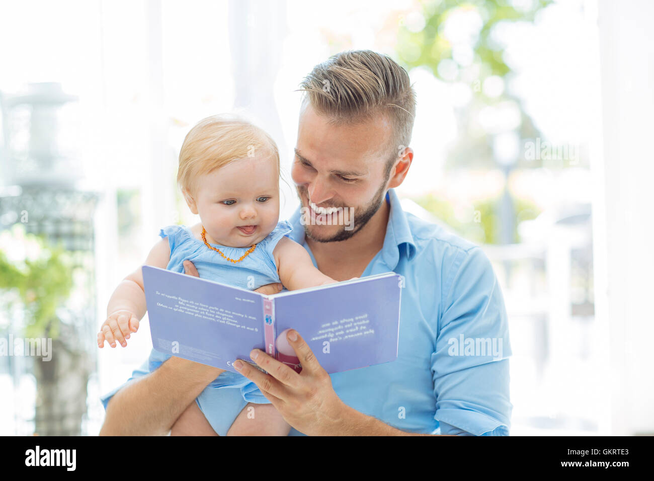 Papá leyendo un libro con su hijita Foto de stock