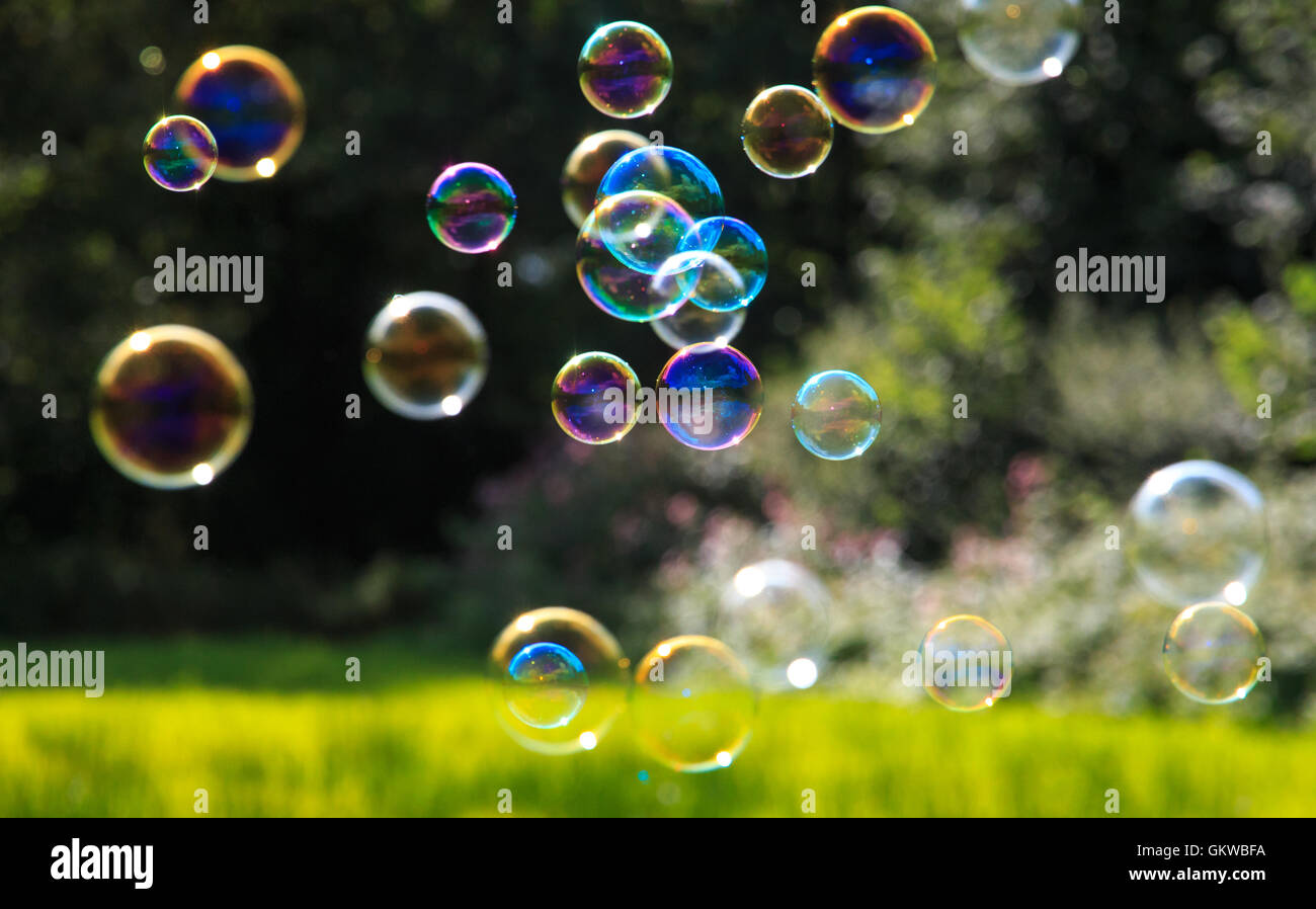 Burbujas de Jabón de colores contra un fondo verde natural con poca profundidad de campo. Foto de stock