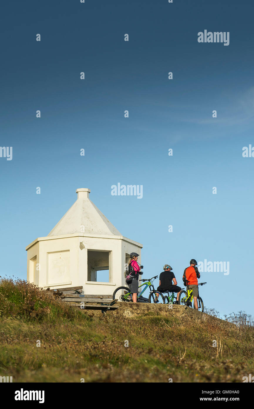 Tres ciclistas de montaña para estar junto a la blanca edificio Mirador en la parte superior de Towan cabecero en Newquay, Cornwall. Foto de stock