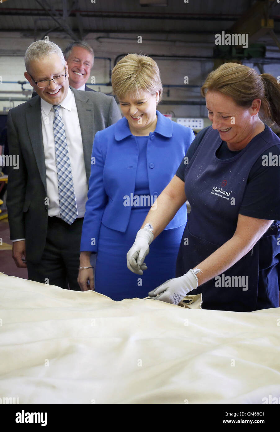 Primer Ministro de Escocia, Nicola Sturgeon está demostrado cómo la piel se recortan por Lesley Jackson (derecha) durante una visita al fabricante de cuero Andrew Muirhouse & Son en Dalmarnock, Glasgow. Foto de stock