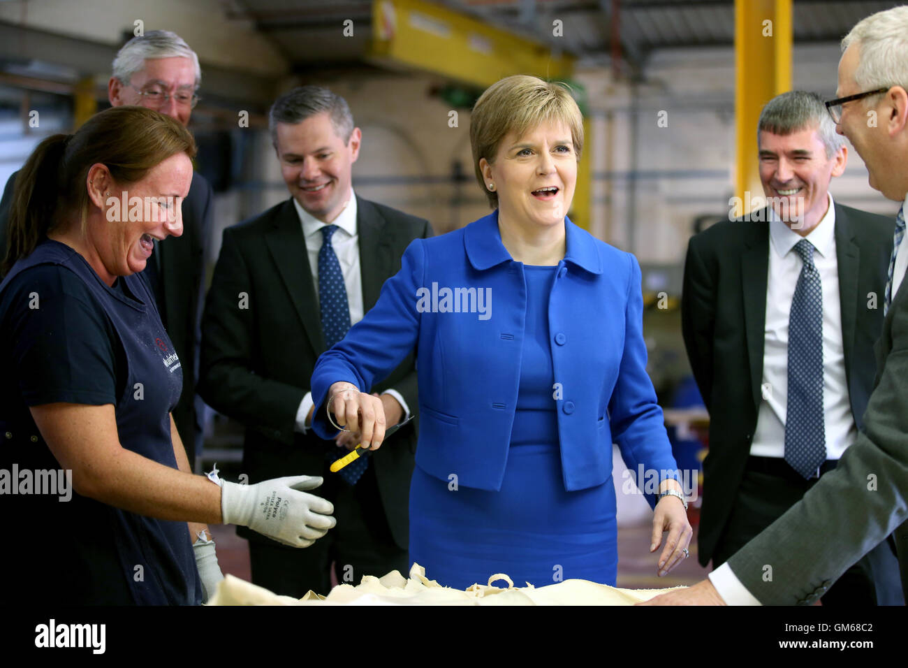 Primer Ministro de Escocia, Nicola Sturgeon está demostrado cómo la piel se recortan por Lesley Jackson (izquierda) durante una visita al fabricante de cuero Andrew Muirhouse & Son en Dalmarnock, Glasgow. Foto de stock