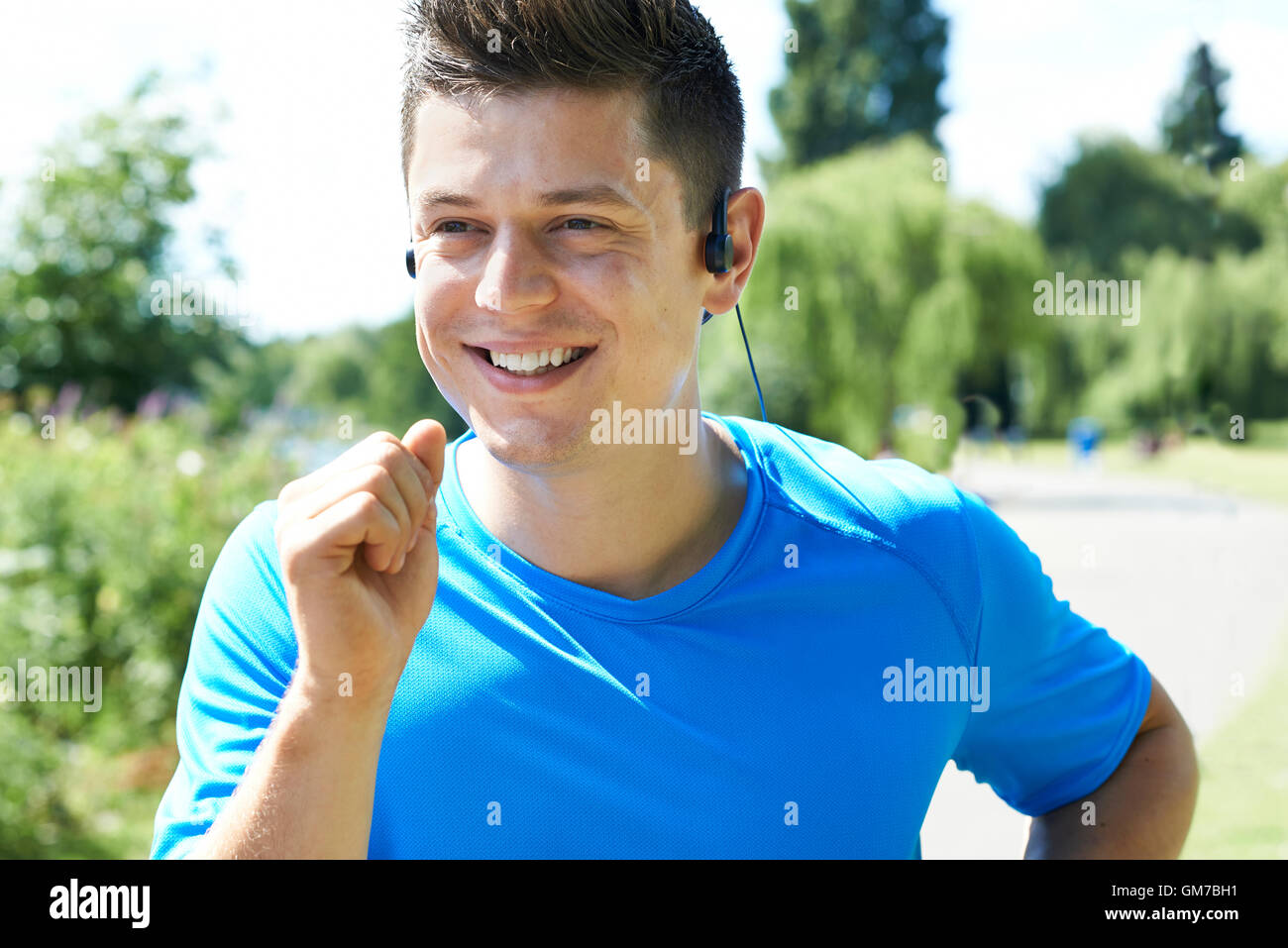 Primer plano de un joven corriendo en el Parque Escuchando música Foto de stock