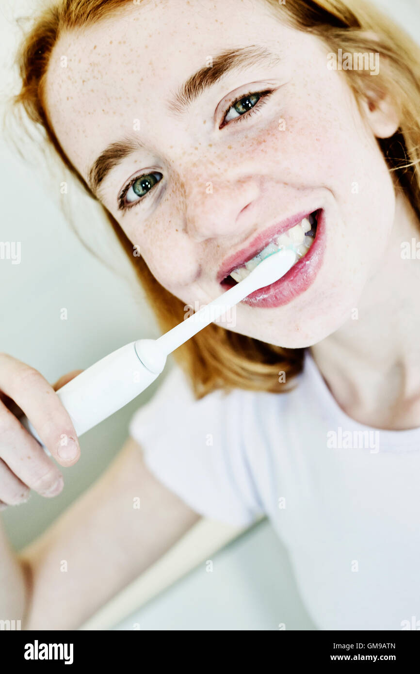 Retrato de niña sonriente cepillarse los dientes con cepillo dental eléctrico Foto de stock