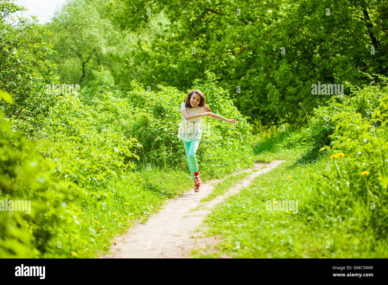 Poco feliz chica corriendo en verano park Foto de stock