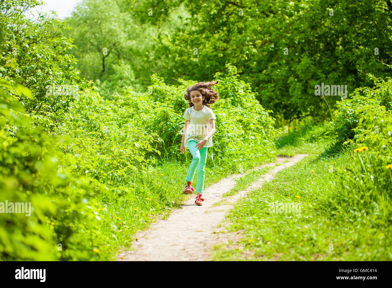 Poco feliz chica corriendo en verano park Foto de stock