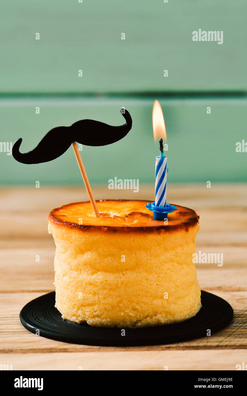 Un cheesecake rematada con un bigote acoplado a un palo y un encendido de  velas de cumpleaños, sobre una superficie de madera rústica contra una  pálida gr Fotografía de stock - Alamy
