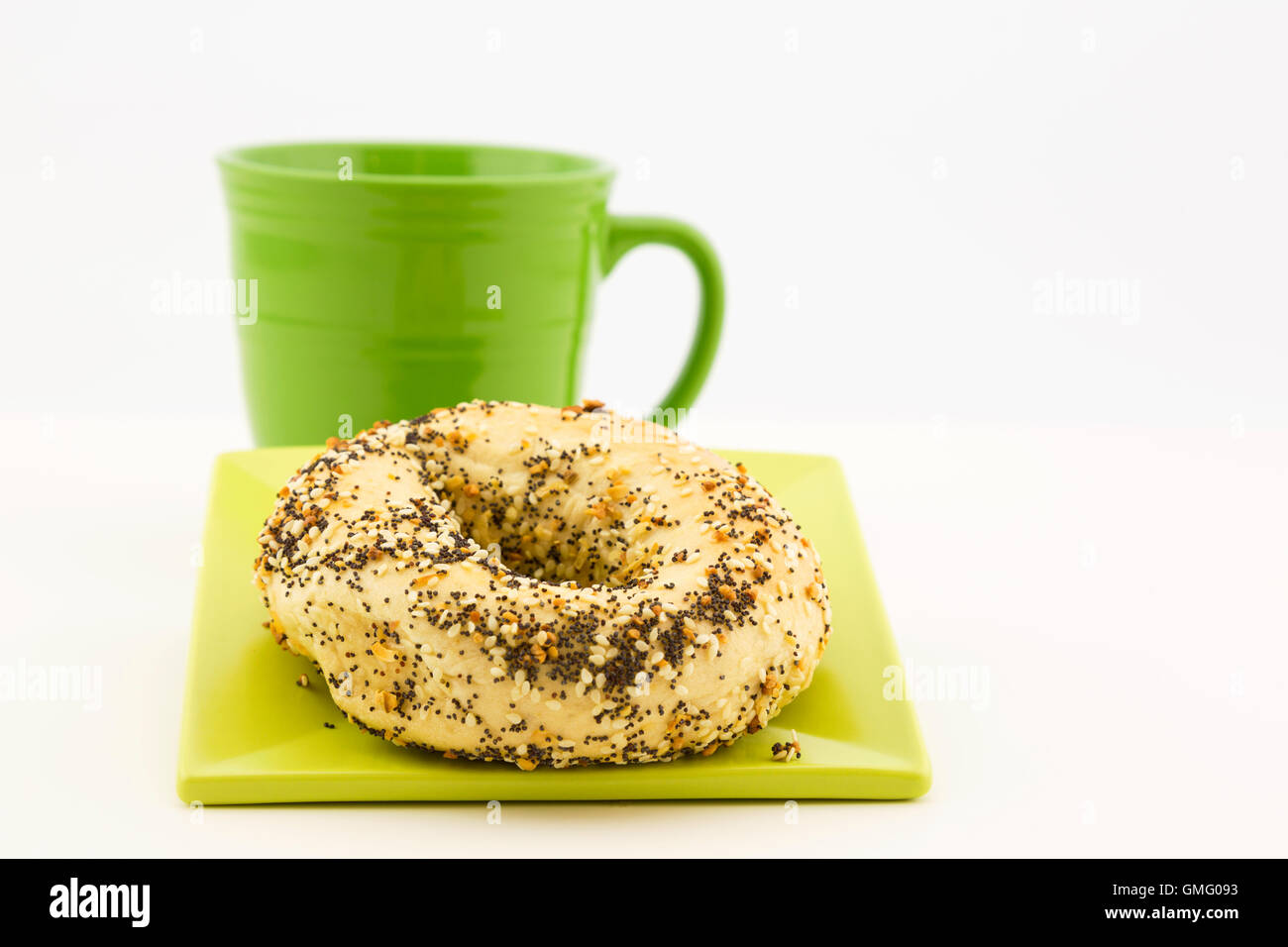 Presentación de café y panecillos con ajo, sésamo y semillas de adormidera como topping y taza verde adyacentes. Foto de stock