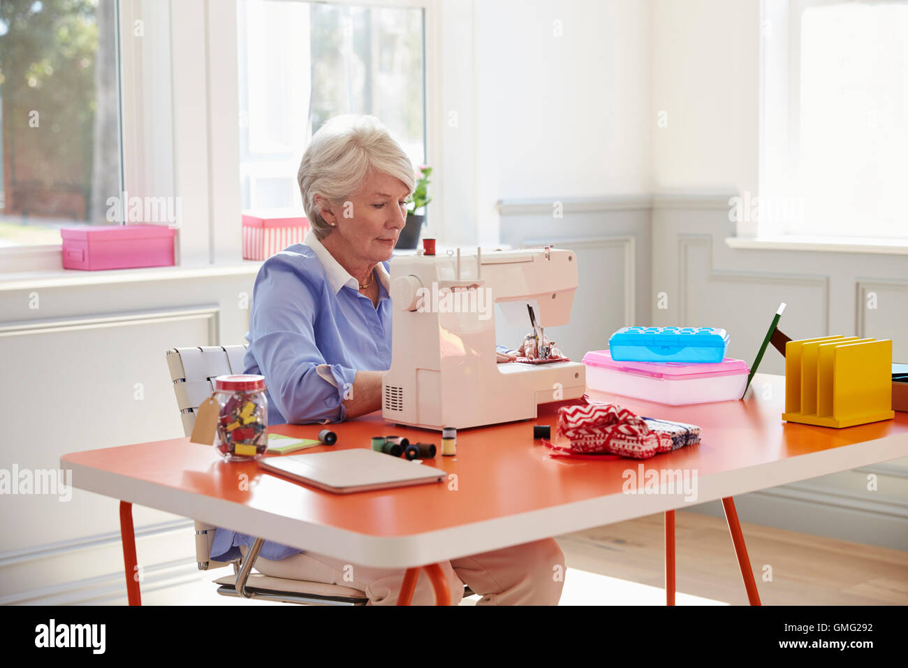 Senior mujer haciendo ropa con máquina de coser en casa Foto de stock