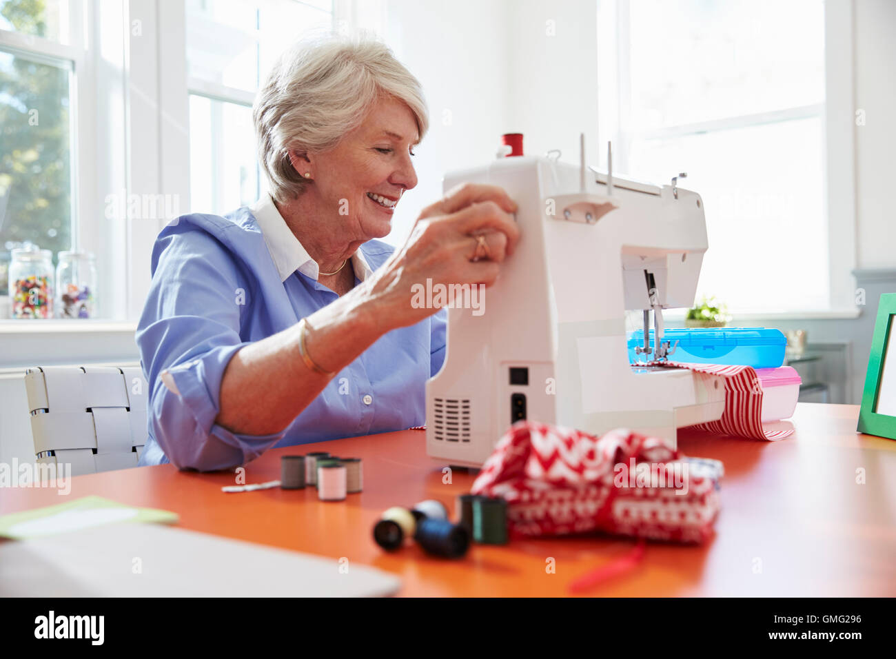 Senior mujer haciendo ropa con máquina de coser en casa Foto de stock