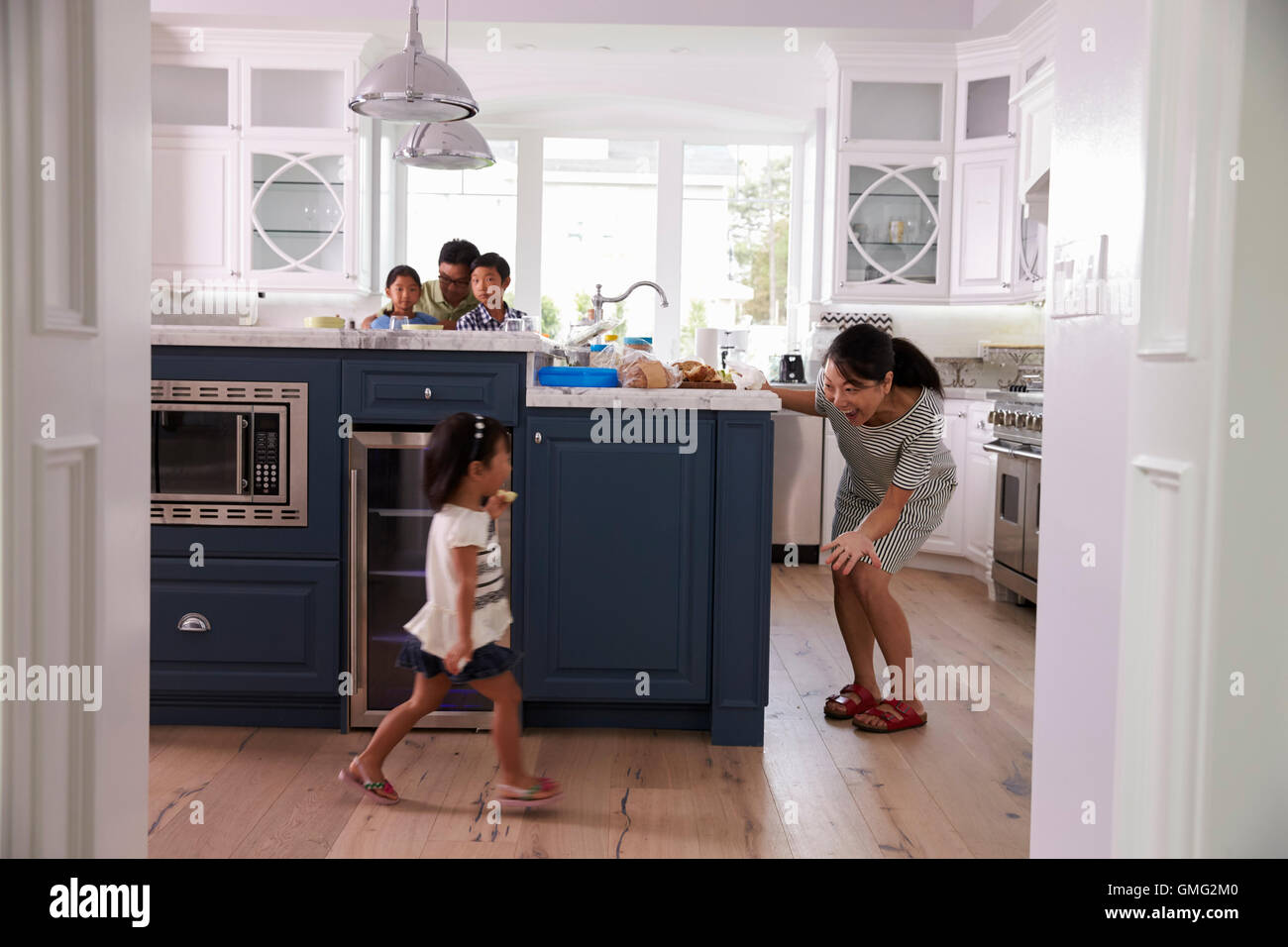 Los padres preparan la comida mientras los niños juegan en la cocina Foto de stock