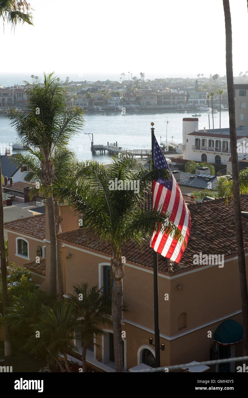 Bandera estadounidense sobrevuela la Corona del Mar casas en un vecindario en la próspera ciudad de Newport Beach con vistas a Newport Bay Foto de stock