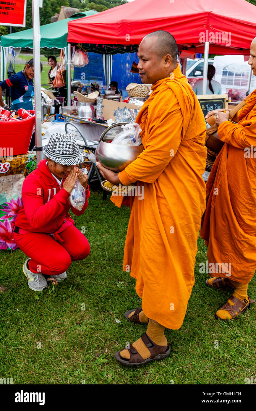 Los Tailandeses ofrecen comida a dos Monjes en el Brighton Festival Tailandés, Preston Park, Brighton, Sussex, Reino Unido Foto de stock