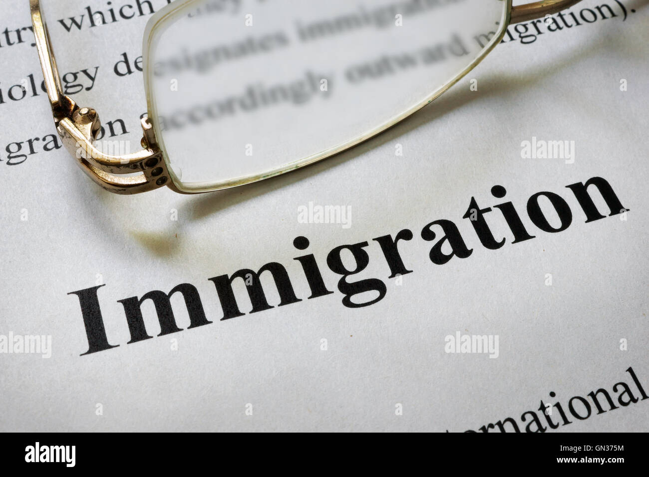 El papel con la palabra inmigración y gafas. Concepto de Derecho. Foto de stock