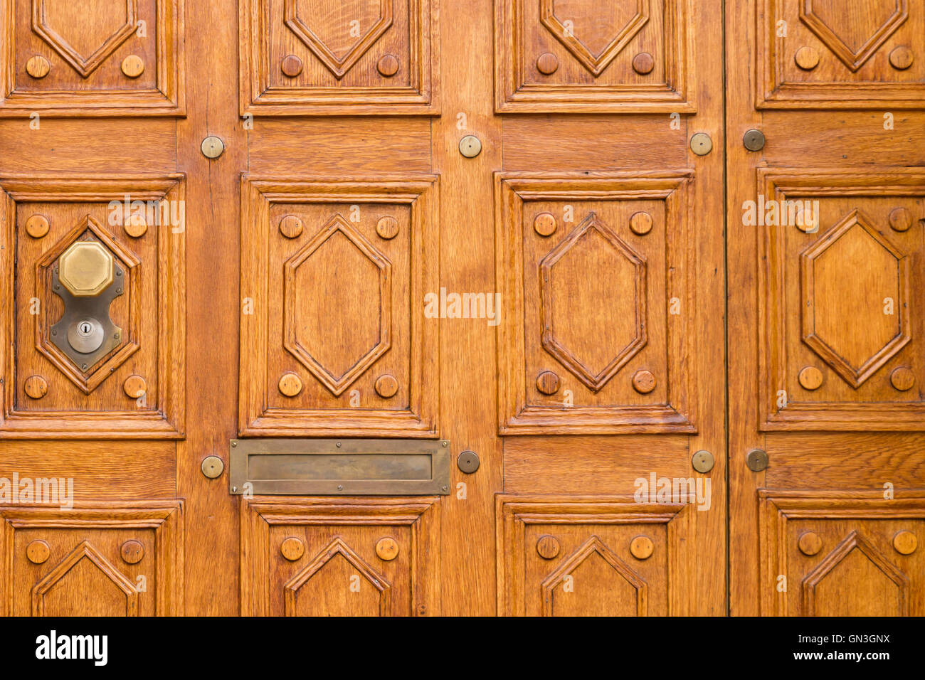 Cerrar vista de una elegante puerta tallada en madera de color marrón claro con patrón cuadrado y un octágono la perilla de la puerta en el lado izquierdo. Foto de stock
