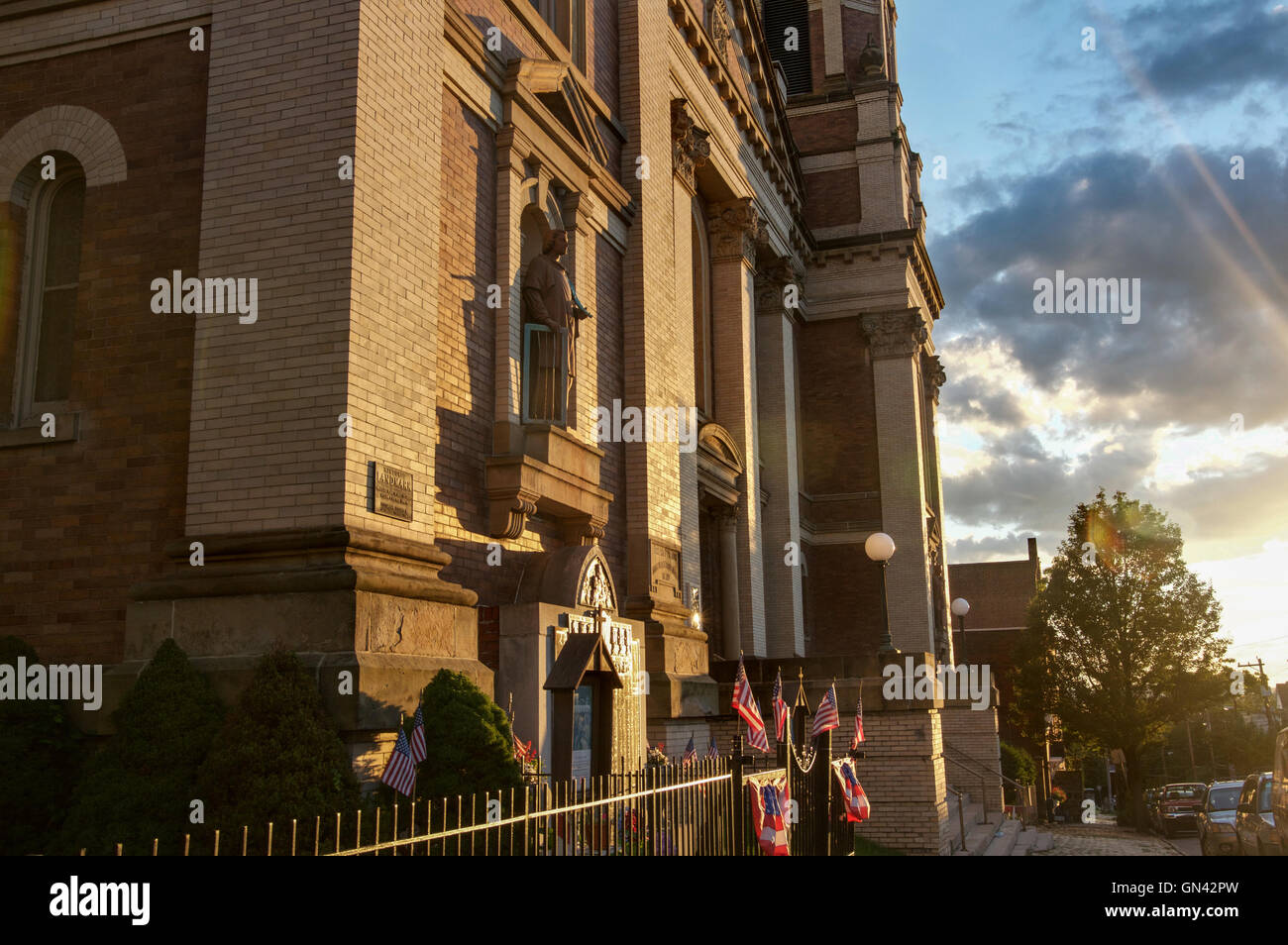Banderas estadounidenses ondean junto a un santuario de Nuestra Señora de Czestochowa en Pittsburgh del barrio Colina polaco Foto de stock