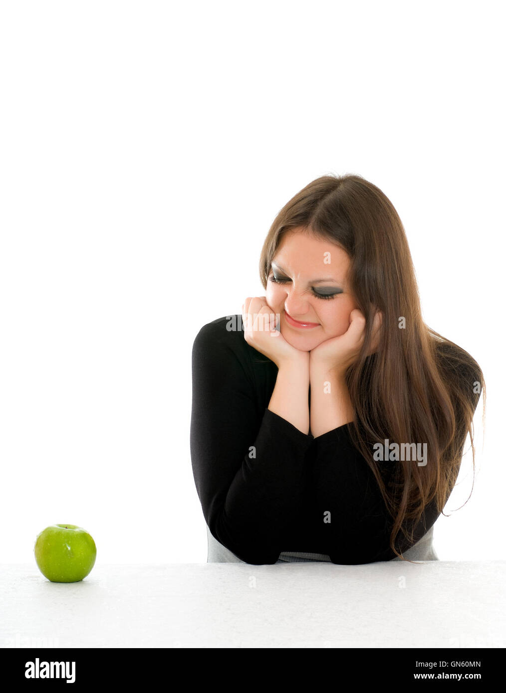 Chica con mueca en su cara y manzana verde Foto de stock