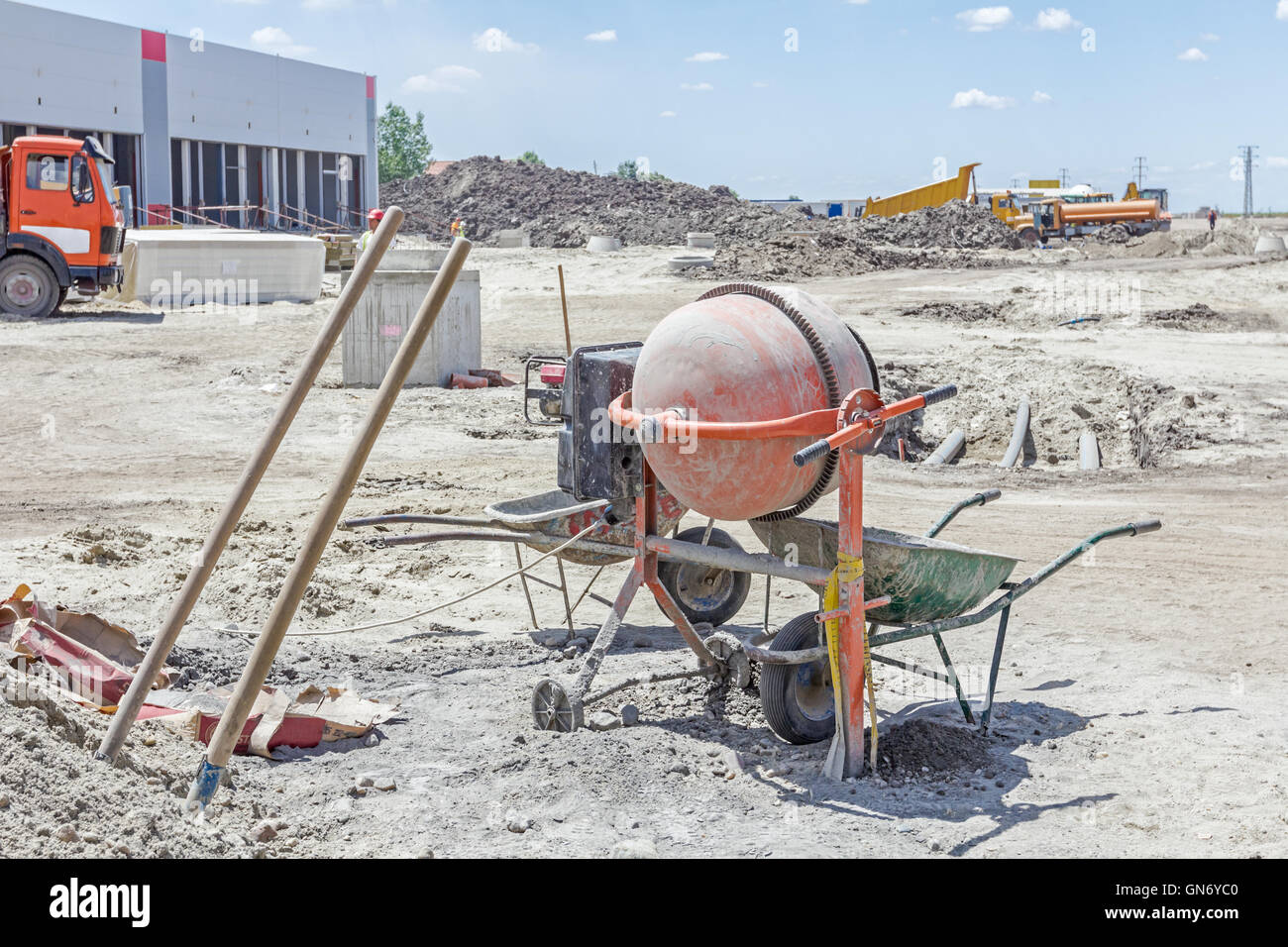 La maquina amasadora la máquina está en el sitio de construcción con dos  carretillas, herramientas, bolsas de cemento y arena Fotografía de stock -  Alamy