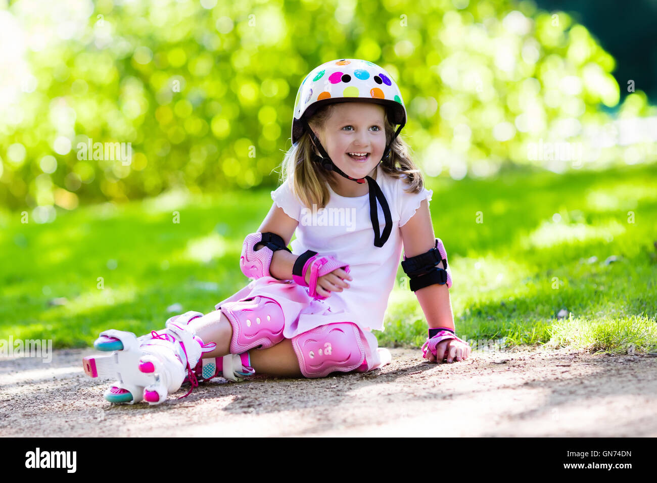 Niña aprendiendo a patines en el parque soleado de verano. Un niño llevaba  protección rodilleras y coderas, casco de seguridad Fotografía de stock -  Alamy