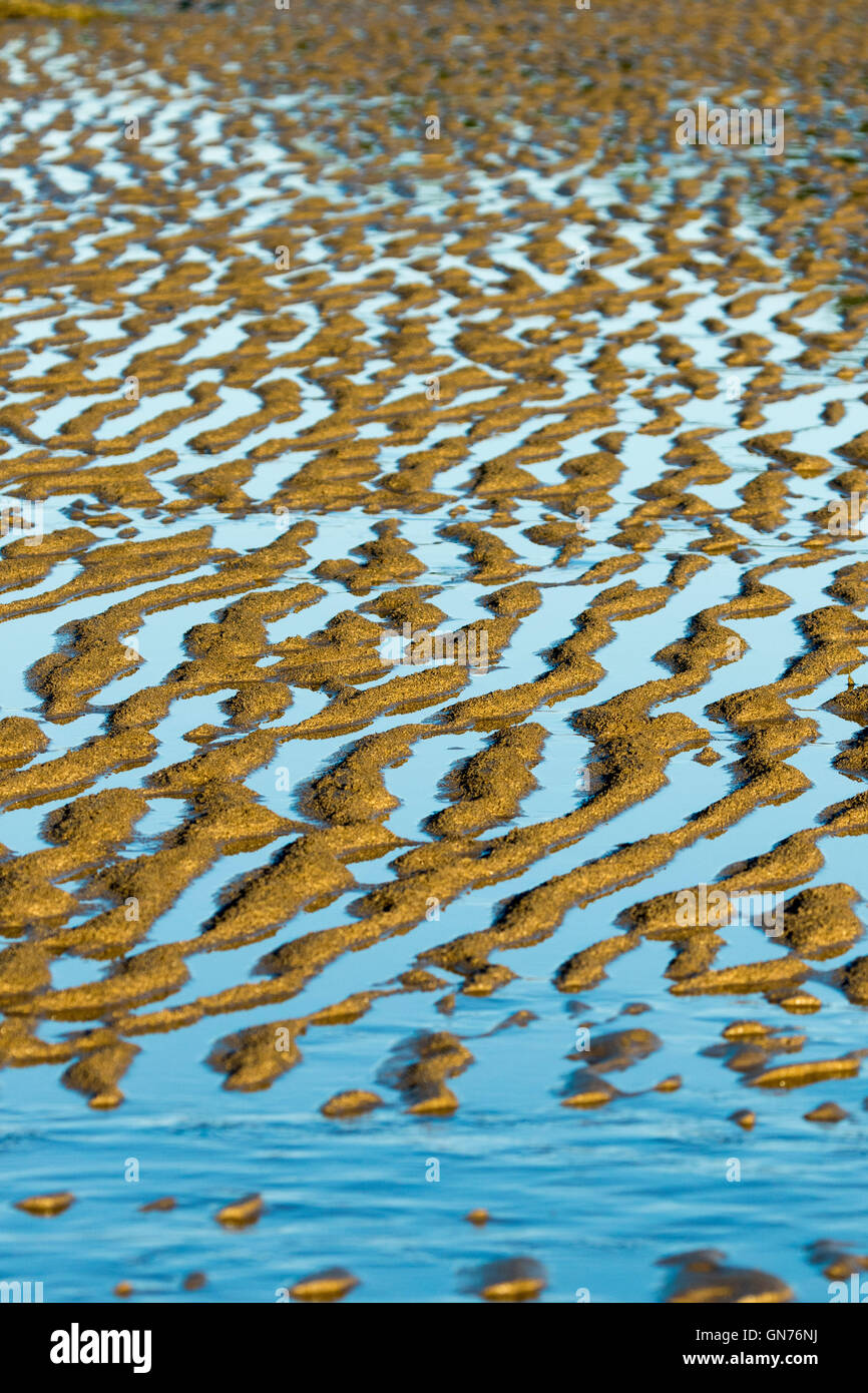 Los patrones naturales únicos, obras de arte creadas con relucientes aguas azul celeste y arroyuelos de arena dorada en la playa Foto de stock