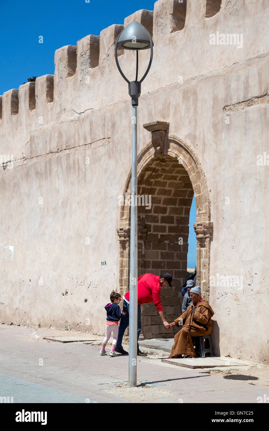 Essaouira, Marruecos. Un acto de caridad: Dar limosna a un mendigo. Foto de stock