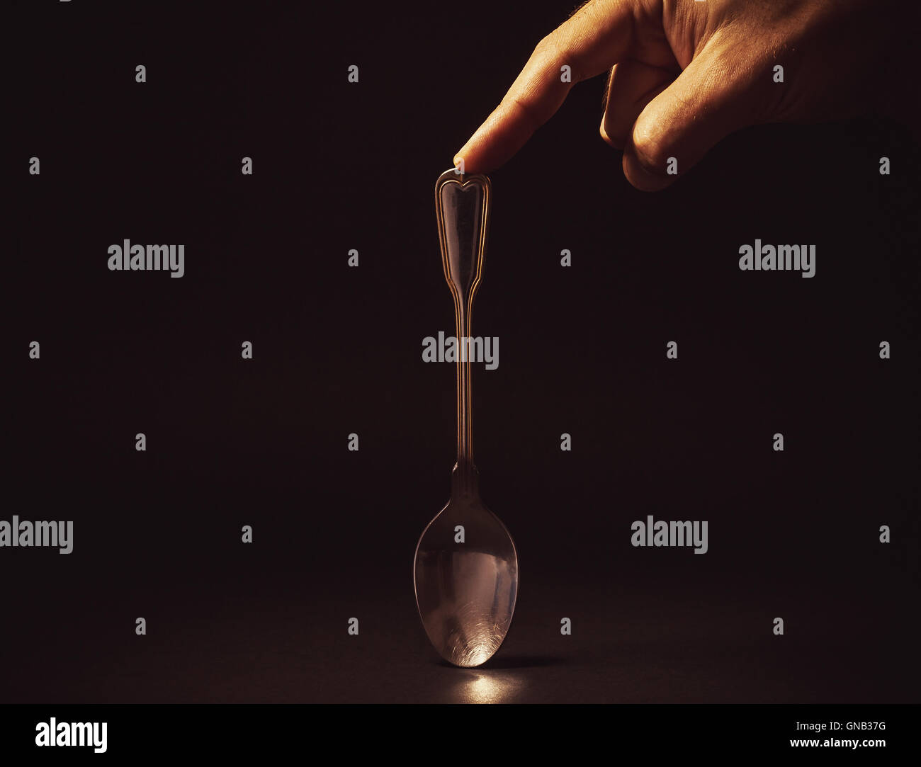 Composición conceptual, la mano del hombre sujetando una cuchara de metal  en el fondo vacío Fotografía de stock - Alamy