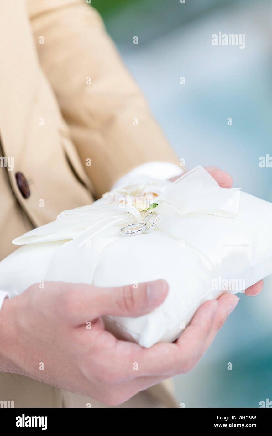 El hermoso anillo de bodas para parejas en la pequeña almohada blanca, listo para la ceremonia de boda Foto de stock