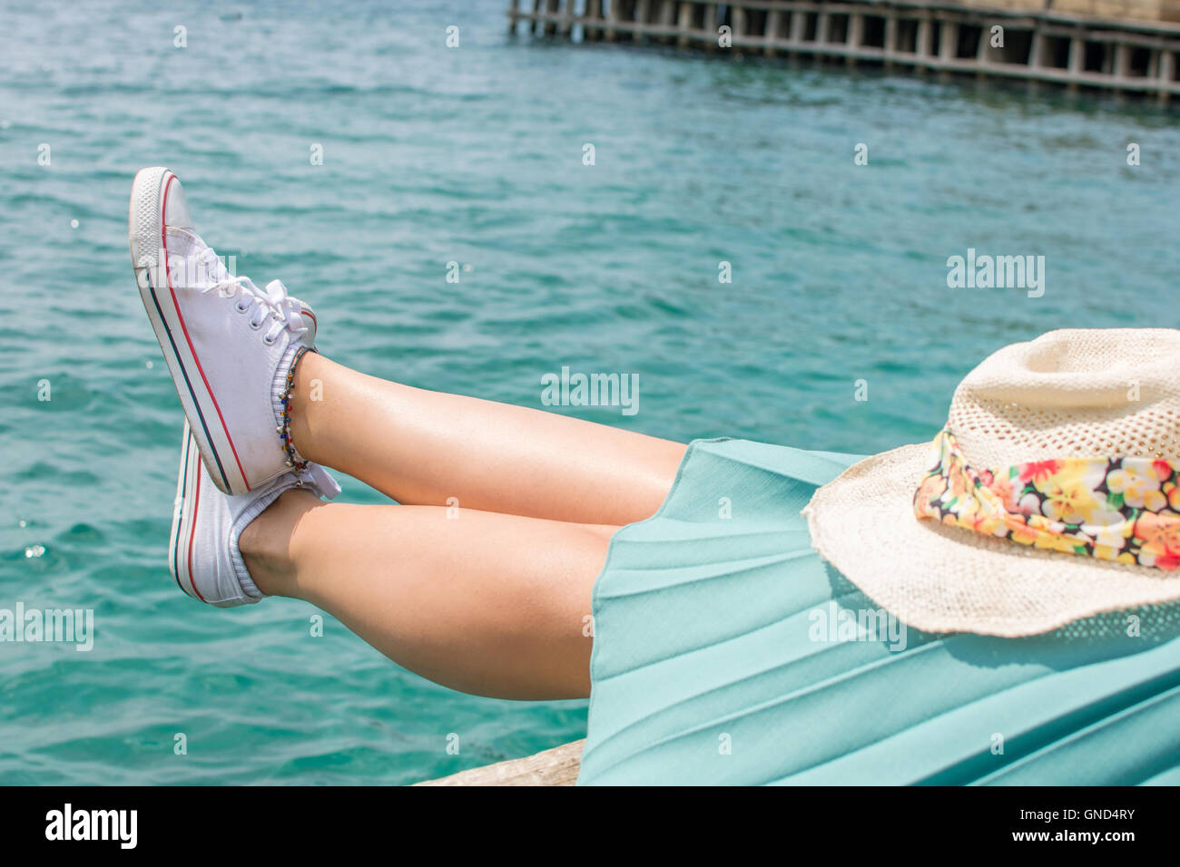Mujer piernas sobre el agua en un dique, relajarse en verano Foto de stock