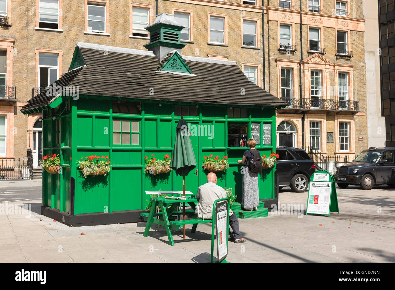 Cabmens refugio, la gente compra alimentos desde un siglo XIX convertido cabman's shelter en Russell Square, Bloomsbury, Londres, Reino Unido. Foto de stock