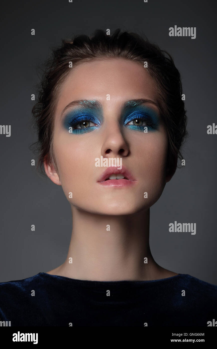 Retrato de una niña modelo con maquillaje azul. Sombreador de ojos, brillante. Foto de stock