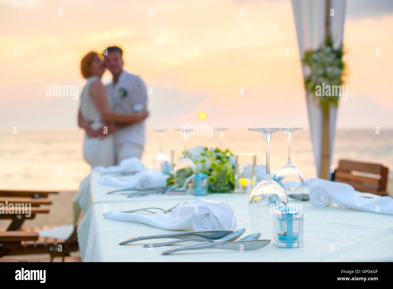 Cena romántica en la playa al atardecer con parejas antecedentes Foto de stock