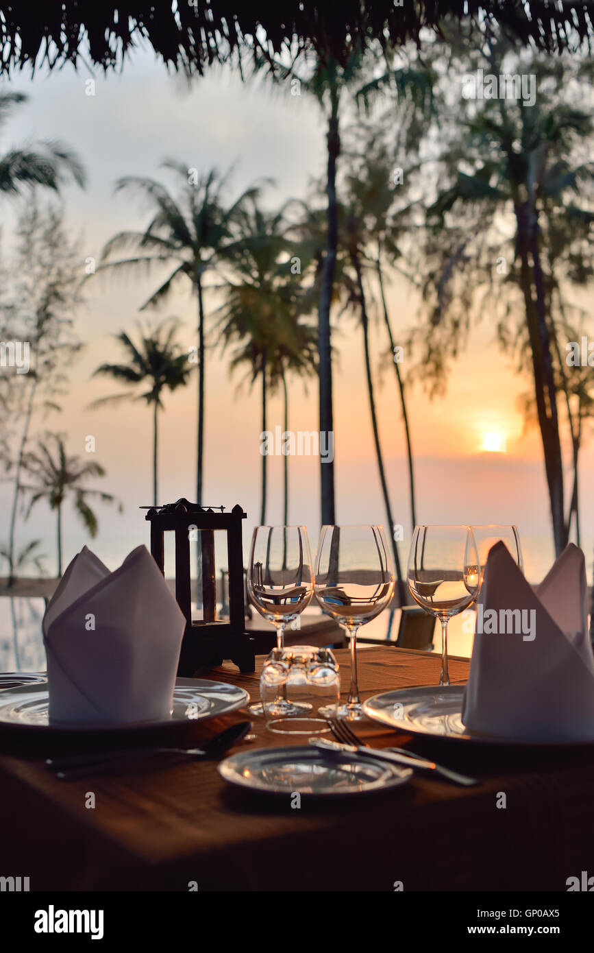 Configuración de una cena romántica en la playa al atardecer. Foto de stock