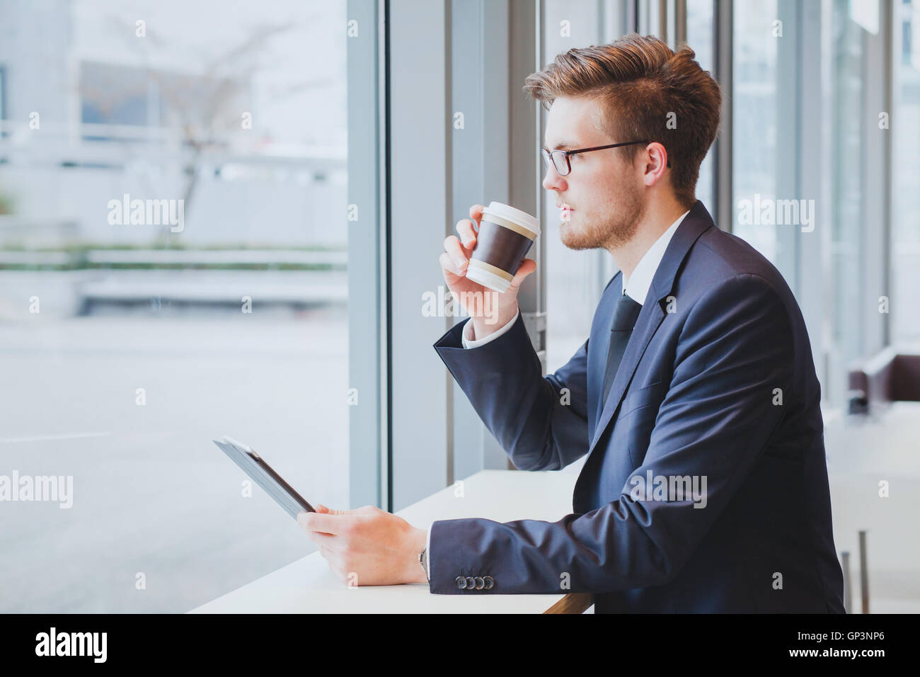 Hombre de negocios pensando, bebiendo café y mirando a la ventana en la moderna cafetería interior Foto de stock