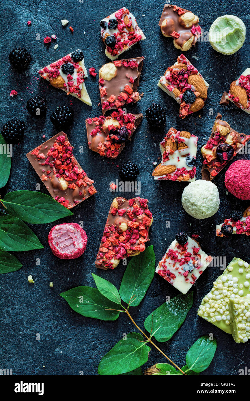 Cortezas de chocolate con frutos secos raspberris (fresas, arándanos, Bayas de Goji,), las nueces y los cereales. Vista superior, encima de la cabeza. Foto de stock