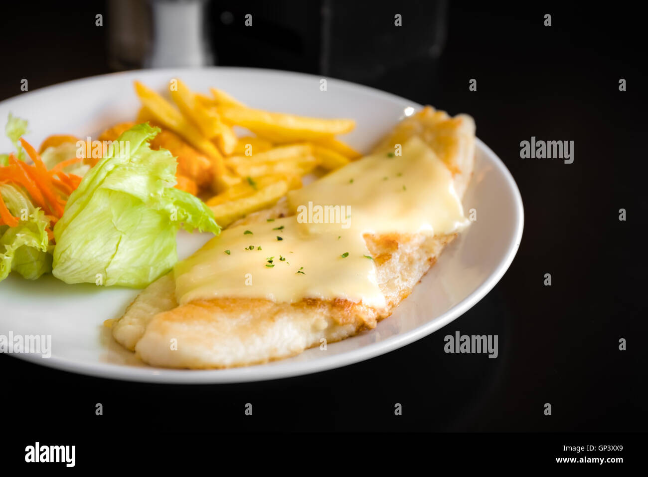 Filete de pescado a la parrilla con ensalada de verduras y patatas fritas. Foto de stock