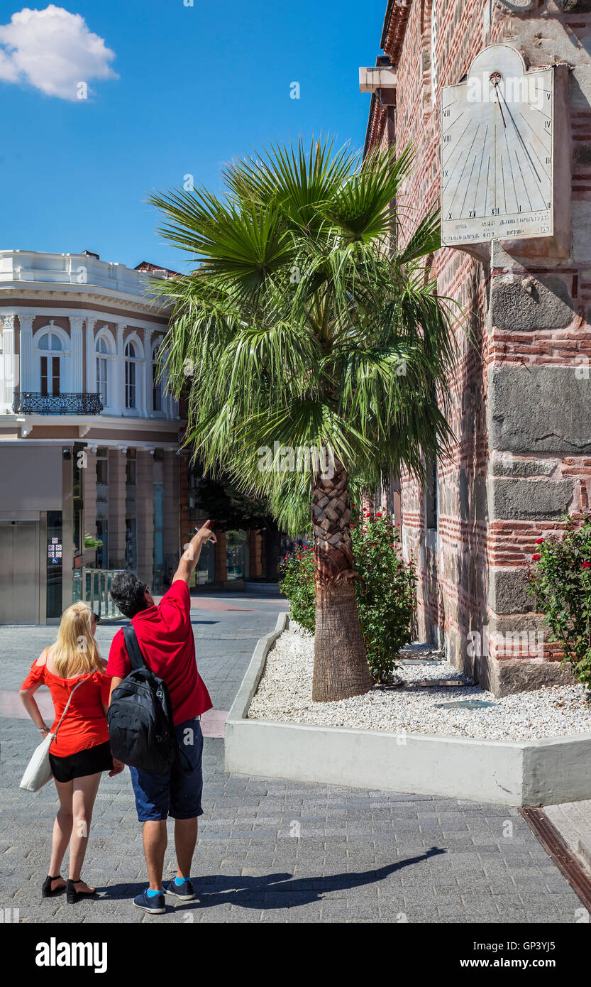 Par turistas mirando reloj solar en la esquina de la Mezquita Djumaya Dzhuaya, o Cuma Camii en turco, centro de Plovdiv en su Foto de stock