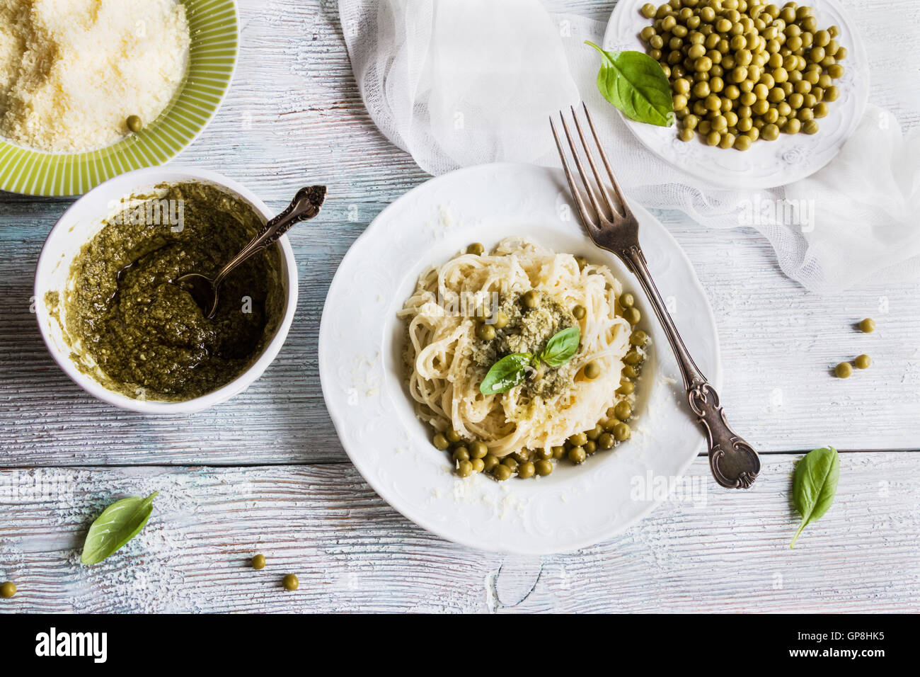 La pasta (espaguetis), judías verdes, salsa pesto, queso parmesano, albahaca fresca. Placas de Vintage, mesa de madera, vista superior. Foto de stock