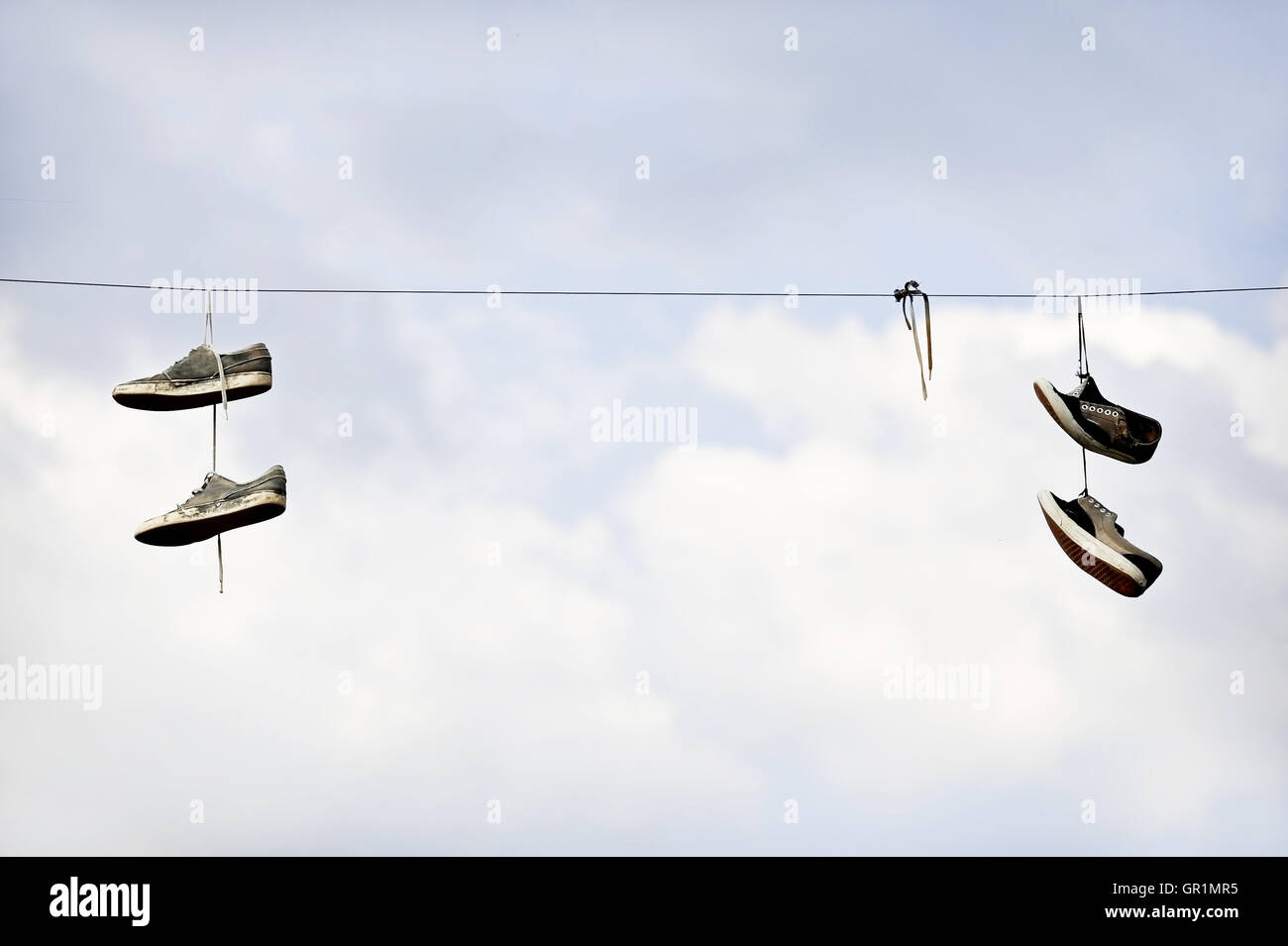 Dos pares de zapatos en un tendido de cable eléctrico con el cielo azul de fondo Foto de stock