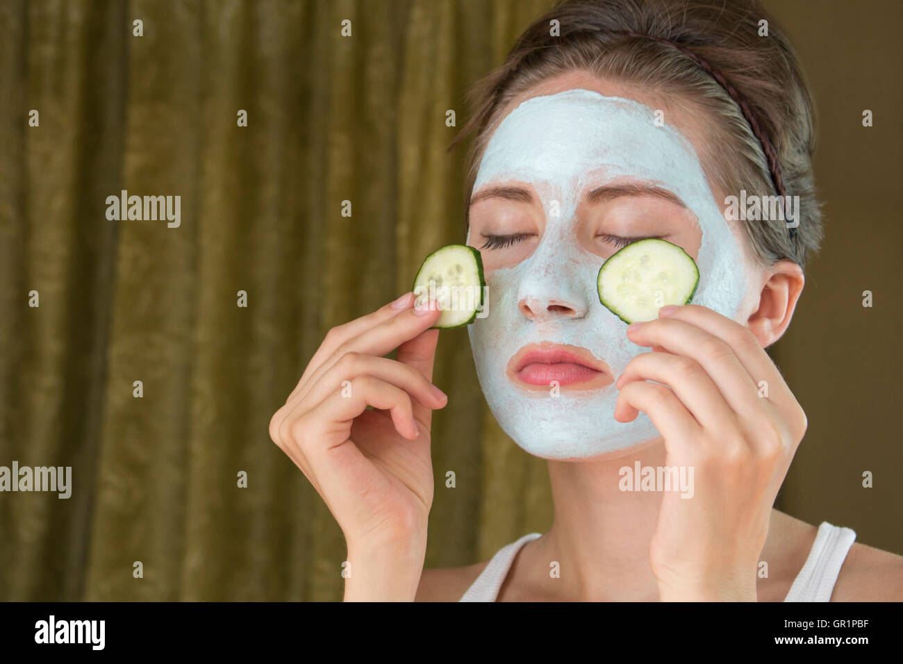 Mujer con máscara facial y rodajas de pepino en sus manos Foto de stock