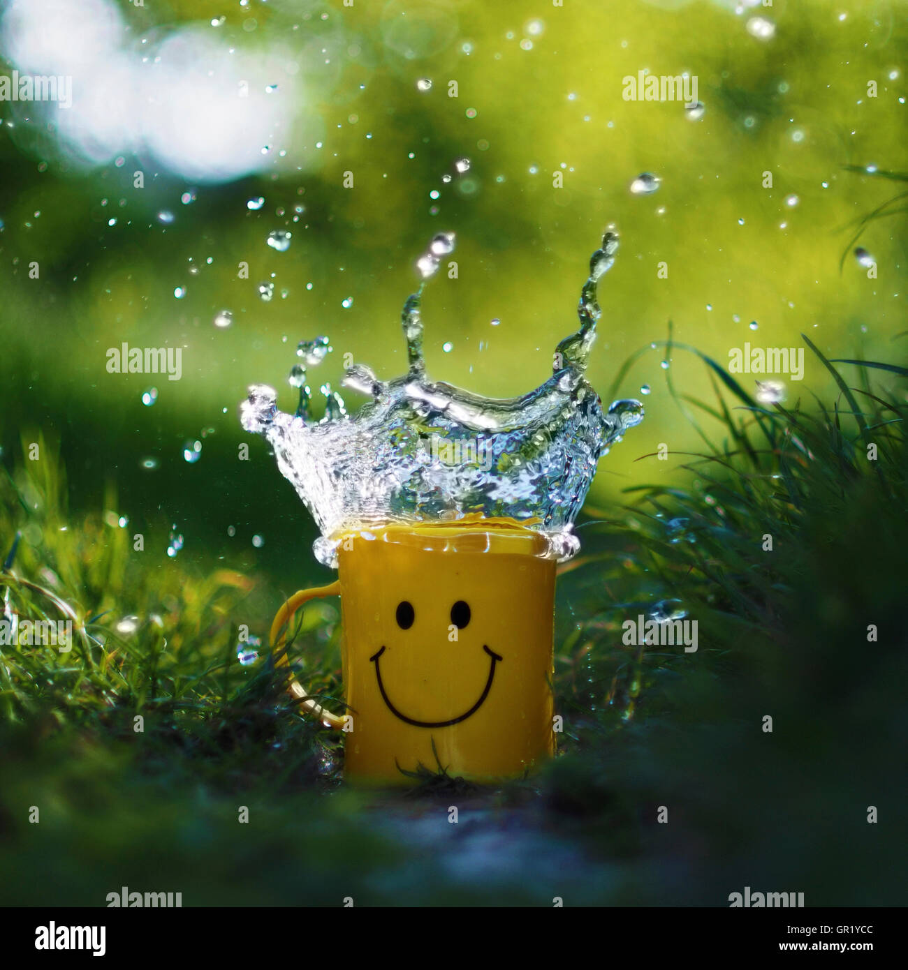 Salpicadura de agua en un vaso de plástico con una cara sonriente. Foto de stock
