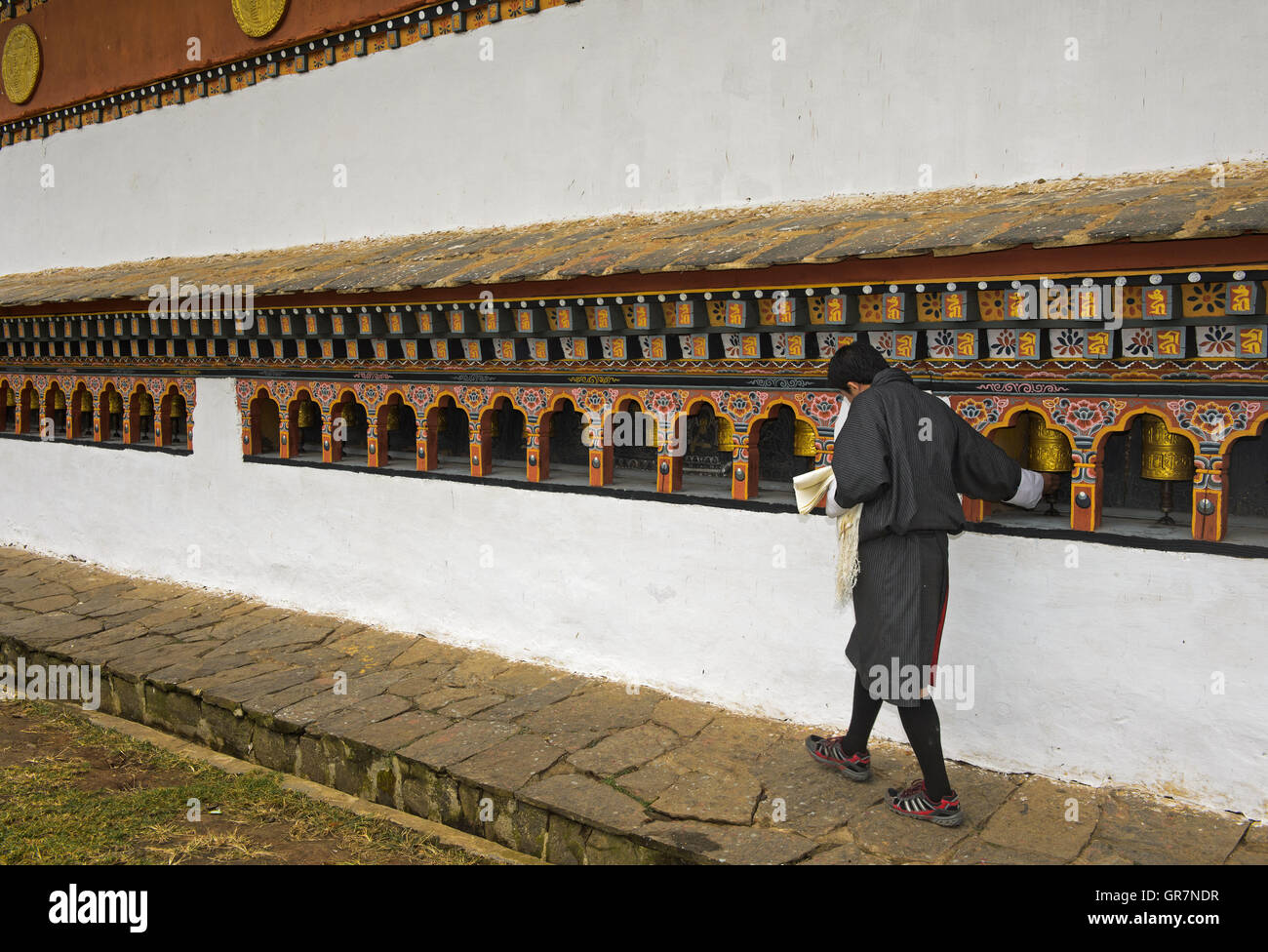 Joven Local que girar los molinos de oración, Monasterio Chime Lhakhang cerca Lobesa, Bhután Foto de stock