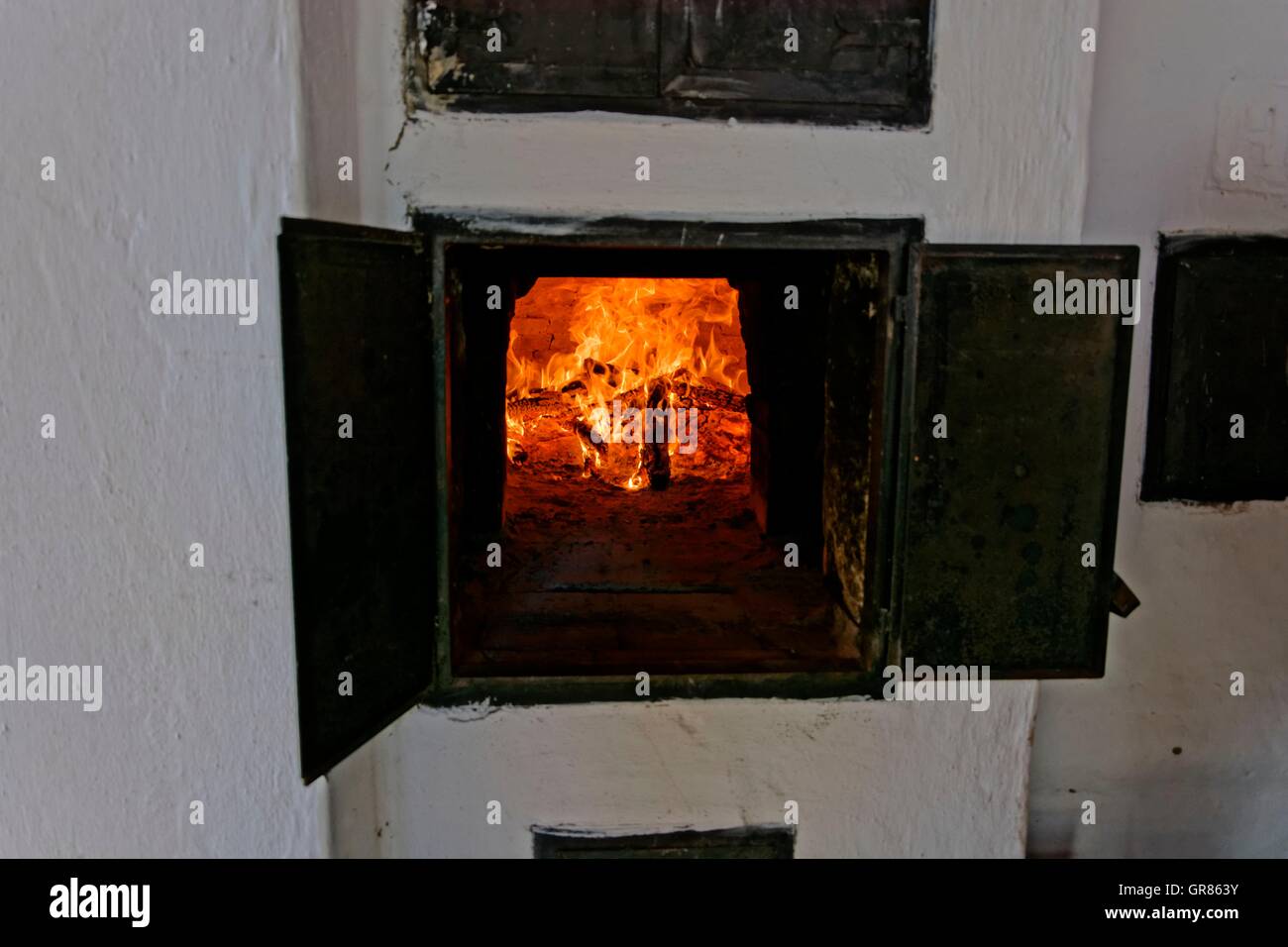 Horno de leña artesanal construido en el exterior con la puerta abierta y  fuego en el interior