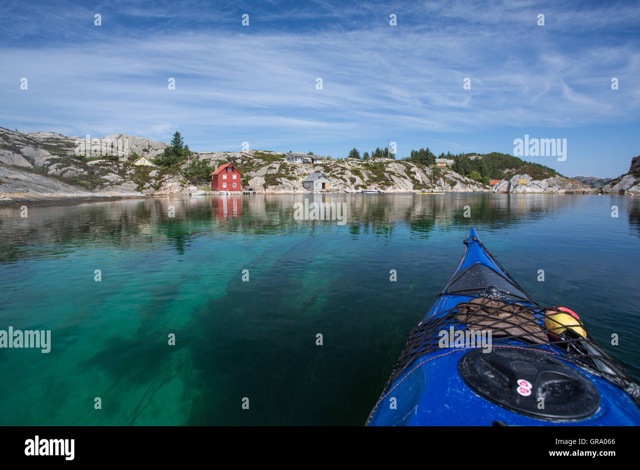 Kayak de mar en noruego el paisaje costero con rocas y una casa roja Foto de stock