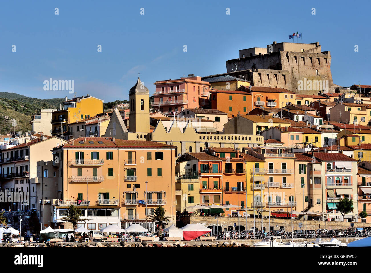Casas coloreadas con el castillo y el puerto de la ciudad de Porto Santo Stefano, en la Toscana, Italia Foto de stock