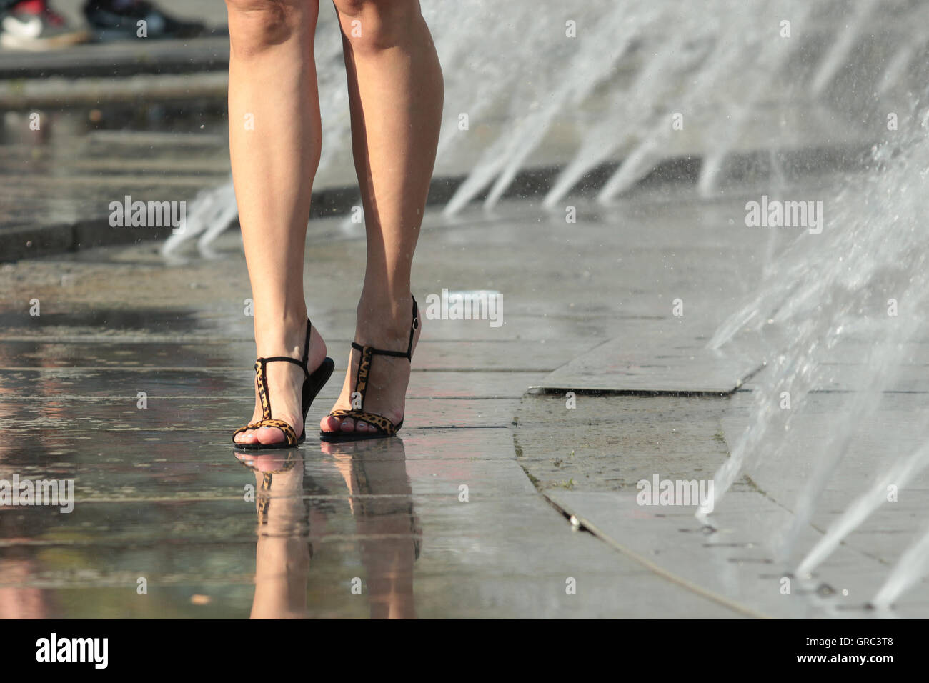 Mujer de piernas en un Fountaun durante la ola de calor Foto de stock